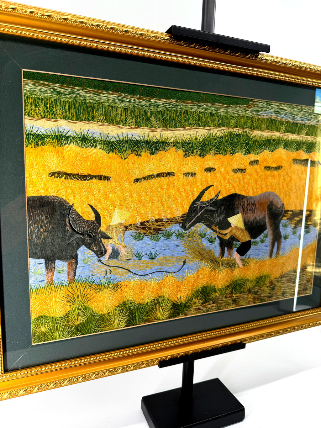 Signed Vietnamese hand-embroidered textile art — water buffalo in rice terraces — angled view from the right showing the gilt frame and glass