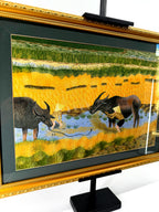 Signed Vietnamese hand-embroidered textile art — water buffalo in rice terraces — angled view from the right showing the gilt frame and glass