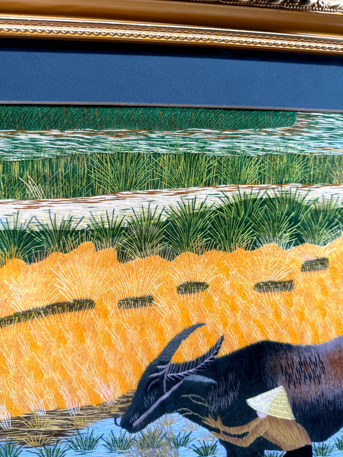 Signed Vietnamese hand-embroidered textile art — water buffalo in rice terraces — detail of the top — green terrace bands above the buffalo