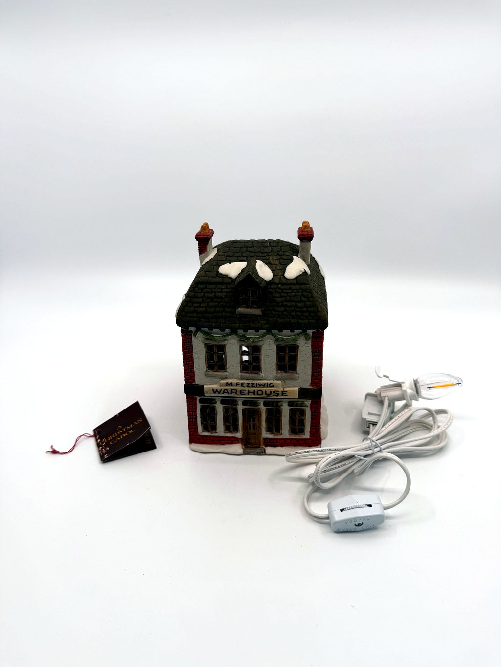 Department 56 M. Fezziwig Warehouse, Dickens' Village, 1986 – shown with its new light cord and A Christmas Carol hang tag