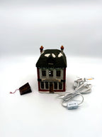 Department 56 M. Fezziwig Warehouse, Dickens' Village, 1986 – shown with its new light cord and A Christmas Carol hang tag