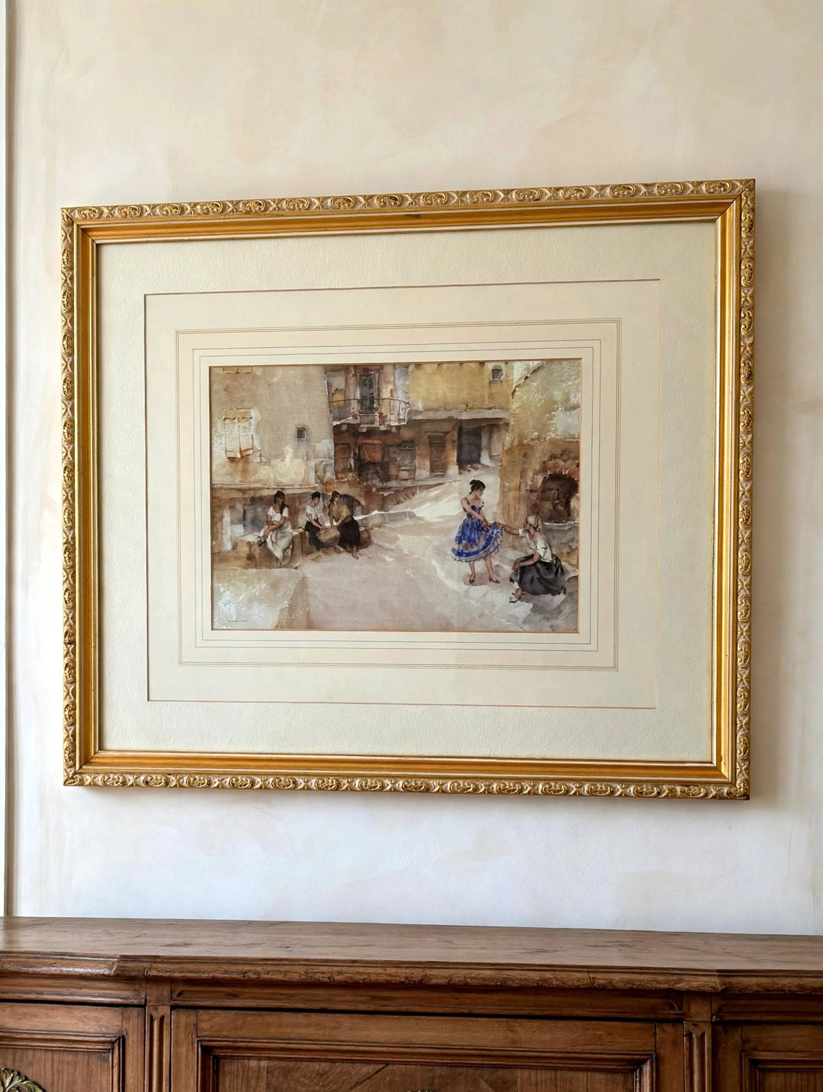 Styled lifestyle photo — the Flint "The Festival Dress, Cordes" framed print shown hanging above an antique sideboard in a vintage living room (display inspiration)