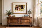 Styled lifestyle photo — the framed Flint Wishing Well print above an antique wooden sideboard in a vintage living room (display inspiration)