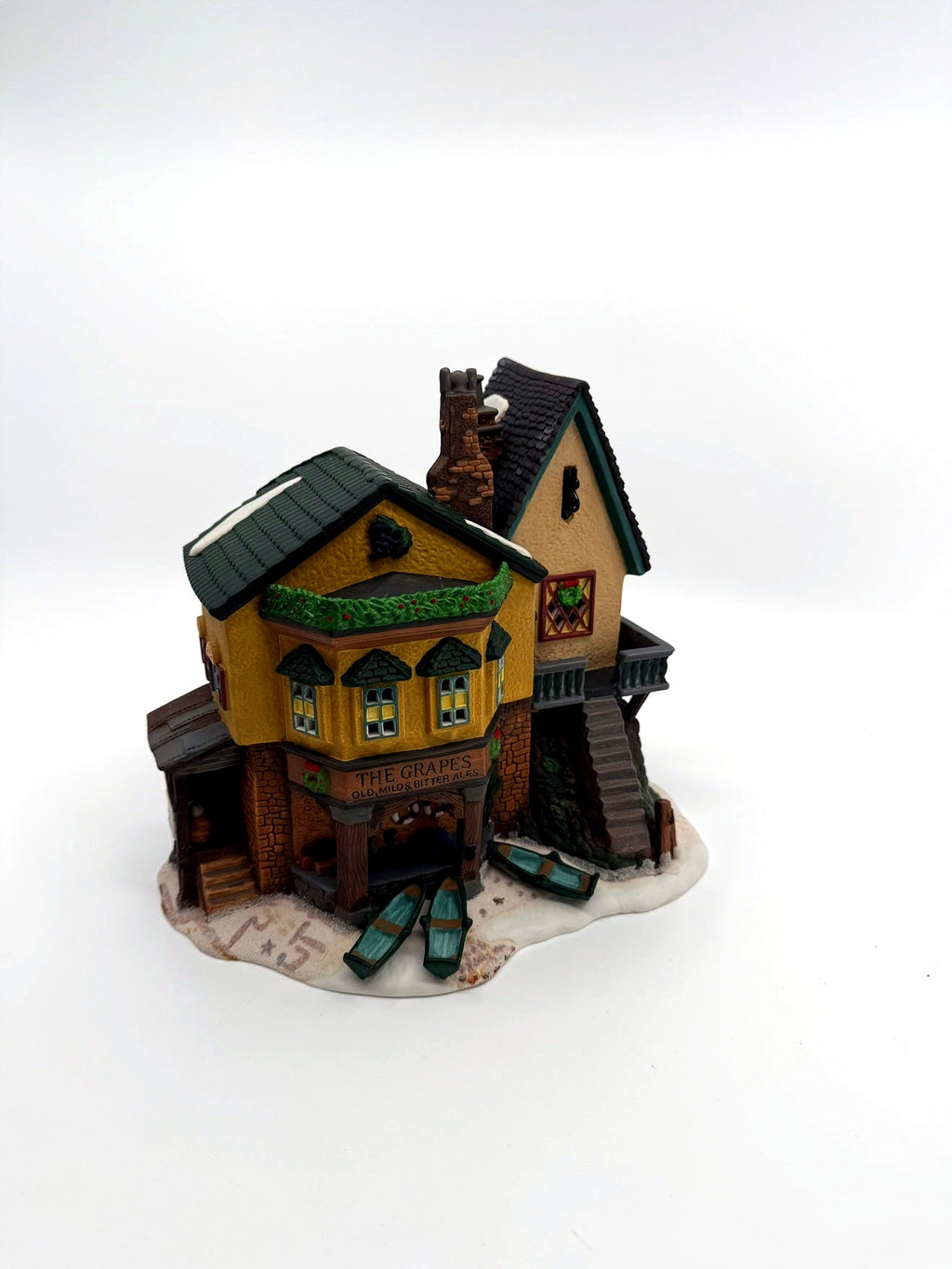 Department 56 Dickens' Village "The Grapes Inn" lighted porcelain building – front three-quarter view showing bay windows, Christmas garland and the rowboats