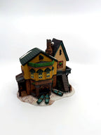 Department 56 Dickens' Village "The Grapes Inn" lighted porcelain building – front three-quarter view showing bay windows, Christmas garland and the rowboats