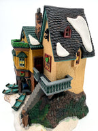 Department 56 Dickens' Village "The Grapes Inn" lighted porcelain building – side view showing the balcony, exterior staircase and tall snow-covered roof