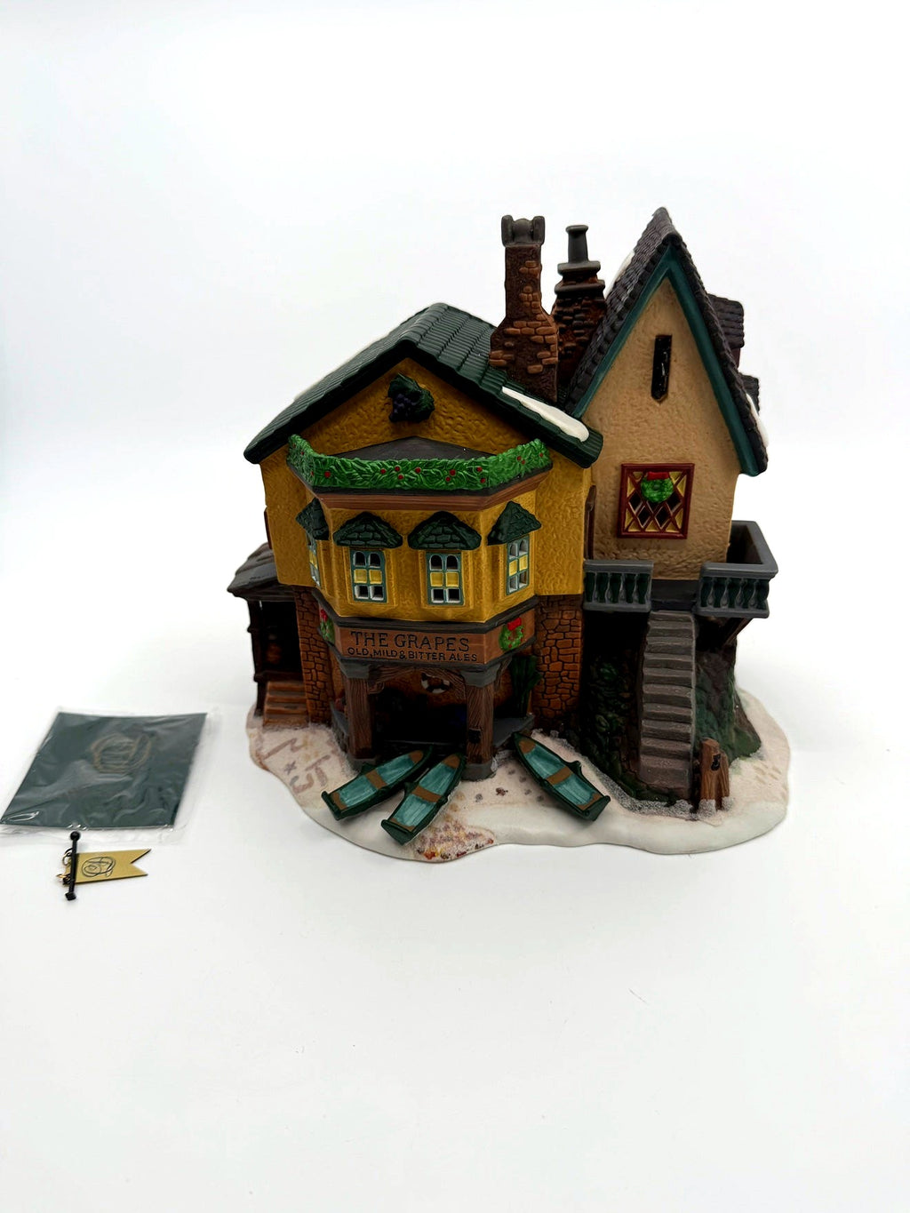 Department 56 Dickens' Village "The Grapes Inn" lighted porcelain building – front view with the hanging flag and paperwork beside the building