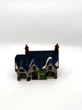 Department 56 Dickens' Village Brownlow House #5553-0, front view — gray stone, deep-blue shingled roof, ivy and Brownlow sign