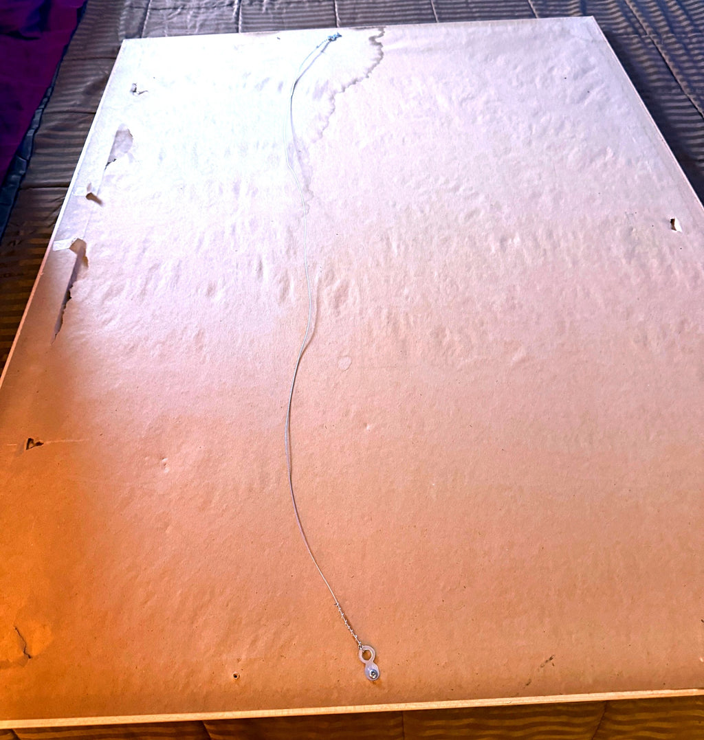 Reverse of the frame — older paper dust backing with age-related tears and discoloration; hanging wire fitted