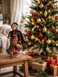 Befana on a side table beside a decorated Christmas tree with wrapped gifts (styled display inspiration)