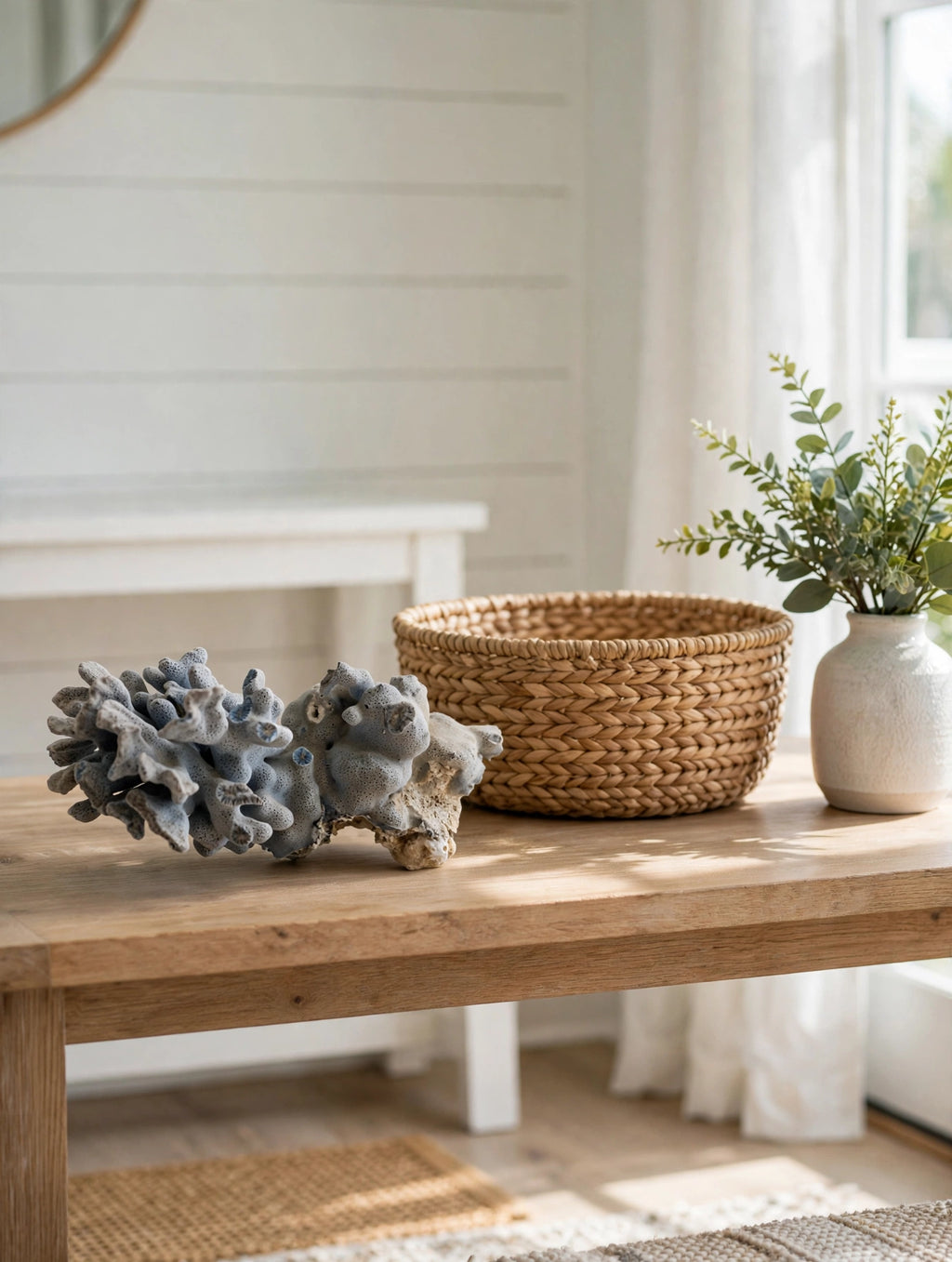 Natural blue-gray branching coral specimen on a sunlit entryway table with a woven basket and greenery (styled display inspiration)