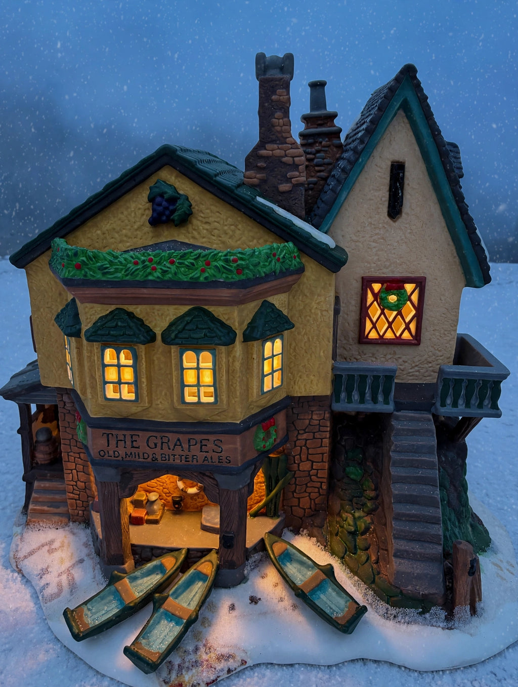 Styled lifestyle photo: The Grapes Inn lit at dusk, windows glowing in falling snow - display inspiration