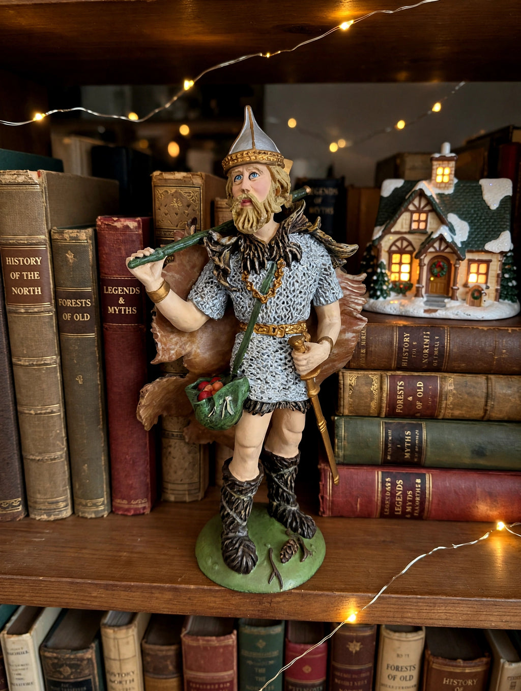 Odin on a bookshelf with a lit Christmas village house (styled display inspiration)