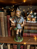 Odin on a bookshelf with a lit Christmas village house (styled display inspiration)