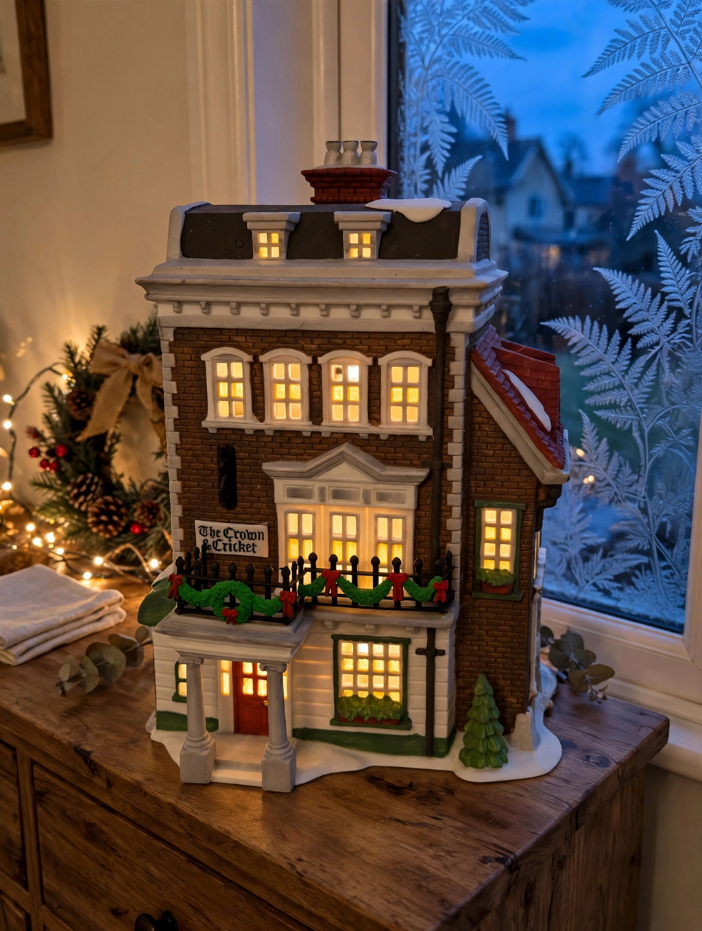 Department 56 Crown & Cricket Inn, Dickens' Village, 1992 First Edition lit on a sideboard beside a frosted window in the evening (styled display inspiration)