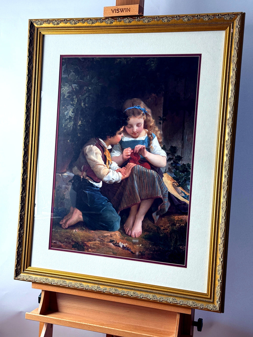 Emile Munier The Knitting Lesson framed art print — front view on an easel from a right angle