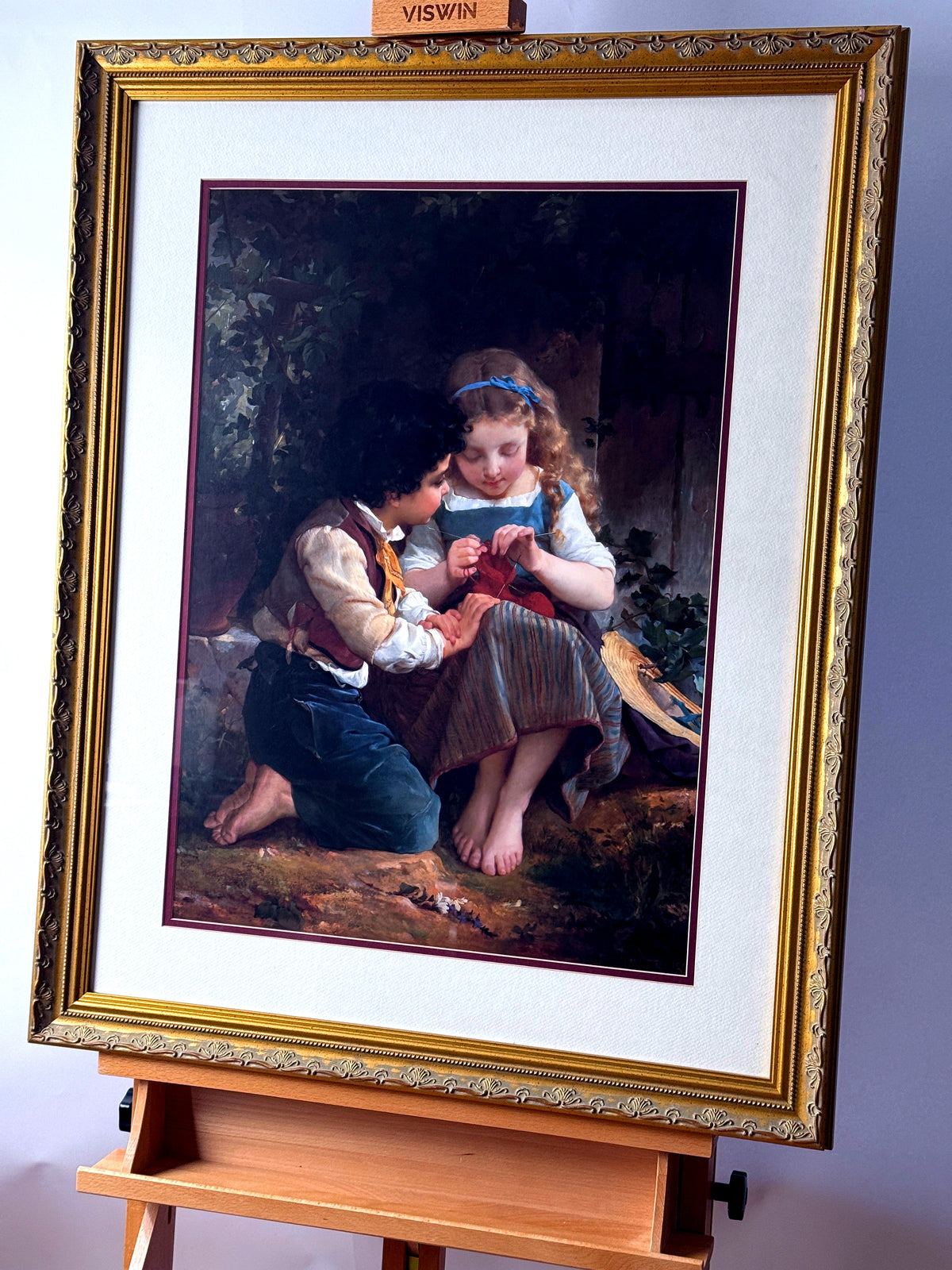 Emile Munier The Knitting Lesson framed art print — front view on an easel from a left angle