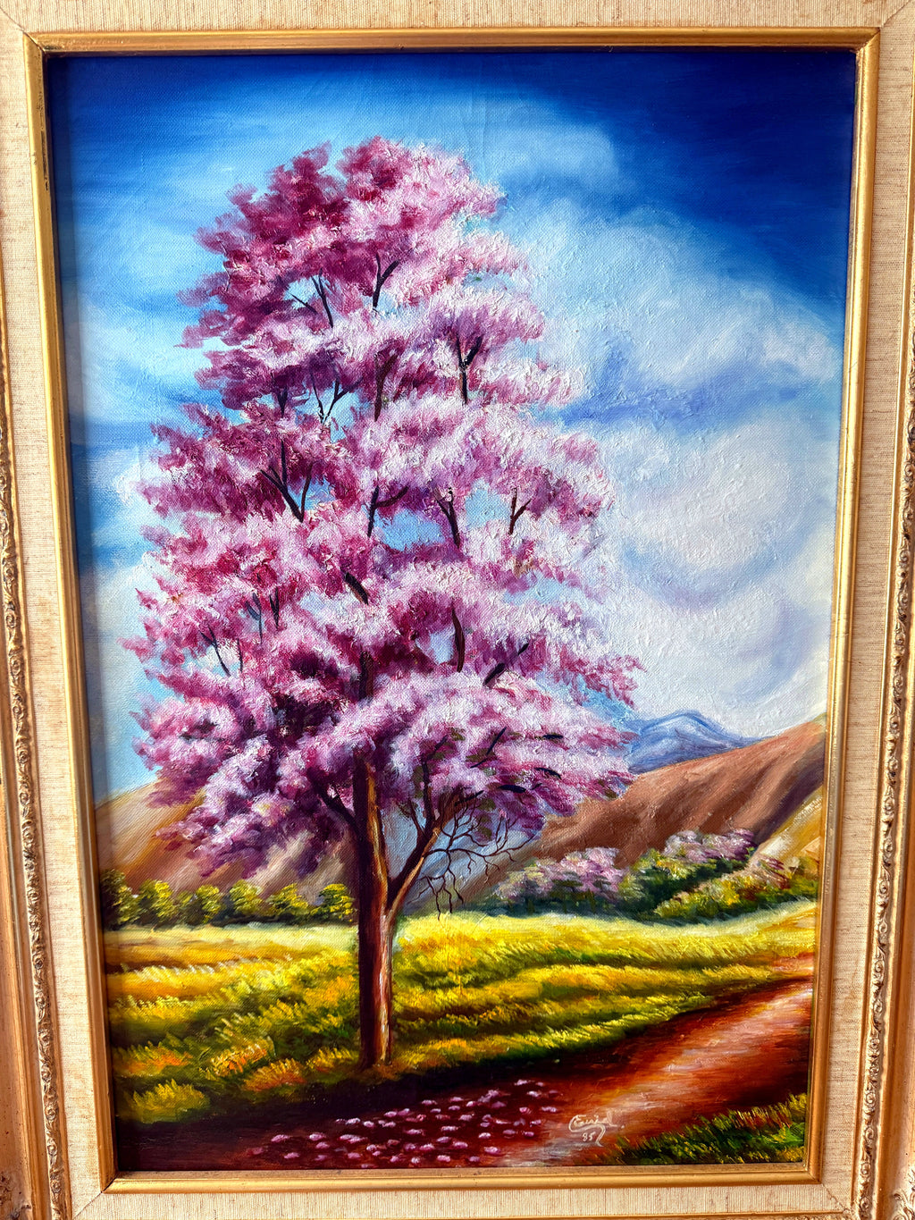 1985 signed oil on canvas pink flowering tree landscape, framed — front view, close crop of the blossom tree and meadow path