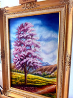 1985 signed oil on canvas pink flowering tree landscape, framed — front view from a left angle
