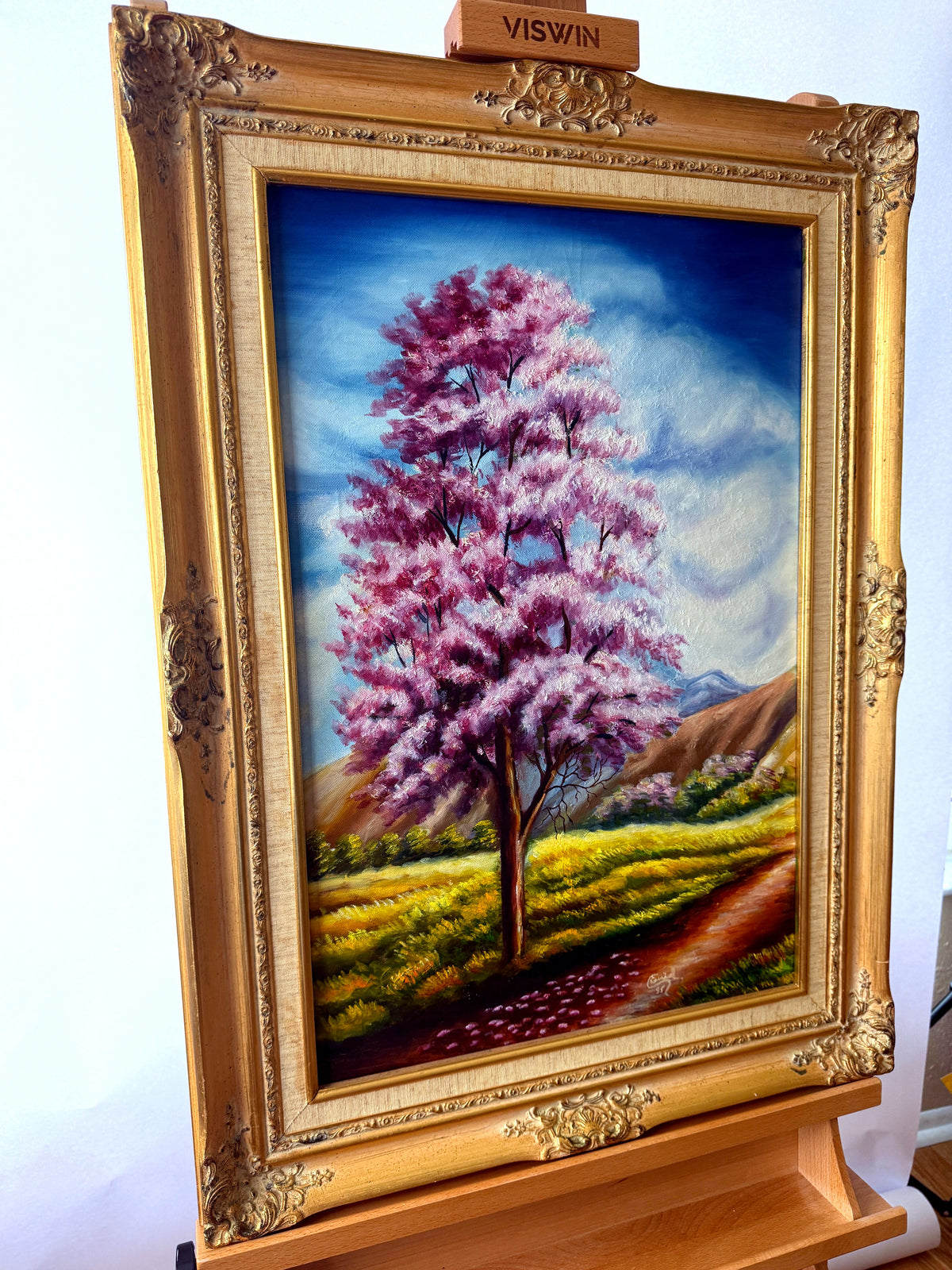 1985 signed oil on canvas pink flowering tree landscape, framed — front view from a right angle