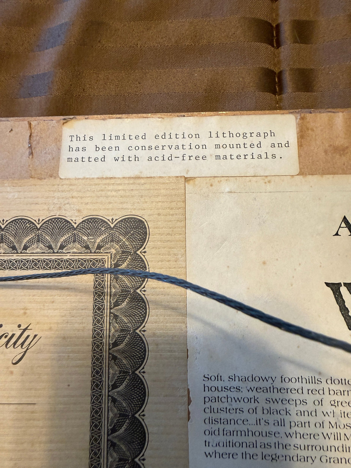 Reverse detail — framer's label noting the lithograph has been conservation mounted and matted with acid-free materials