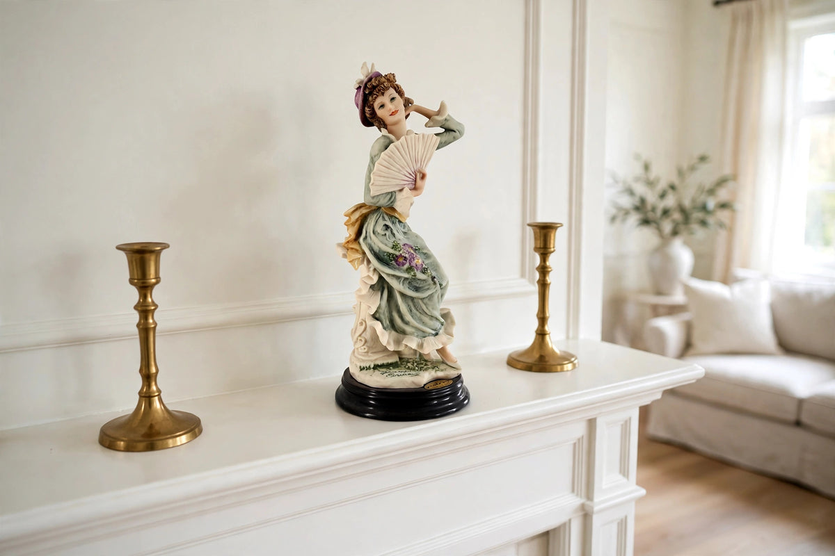 Styled lifestyle photo — the Armani "Violet" figurine on a white fireplace mantel with brass candlesticks in a bright living room (display inspiration)