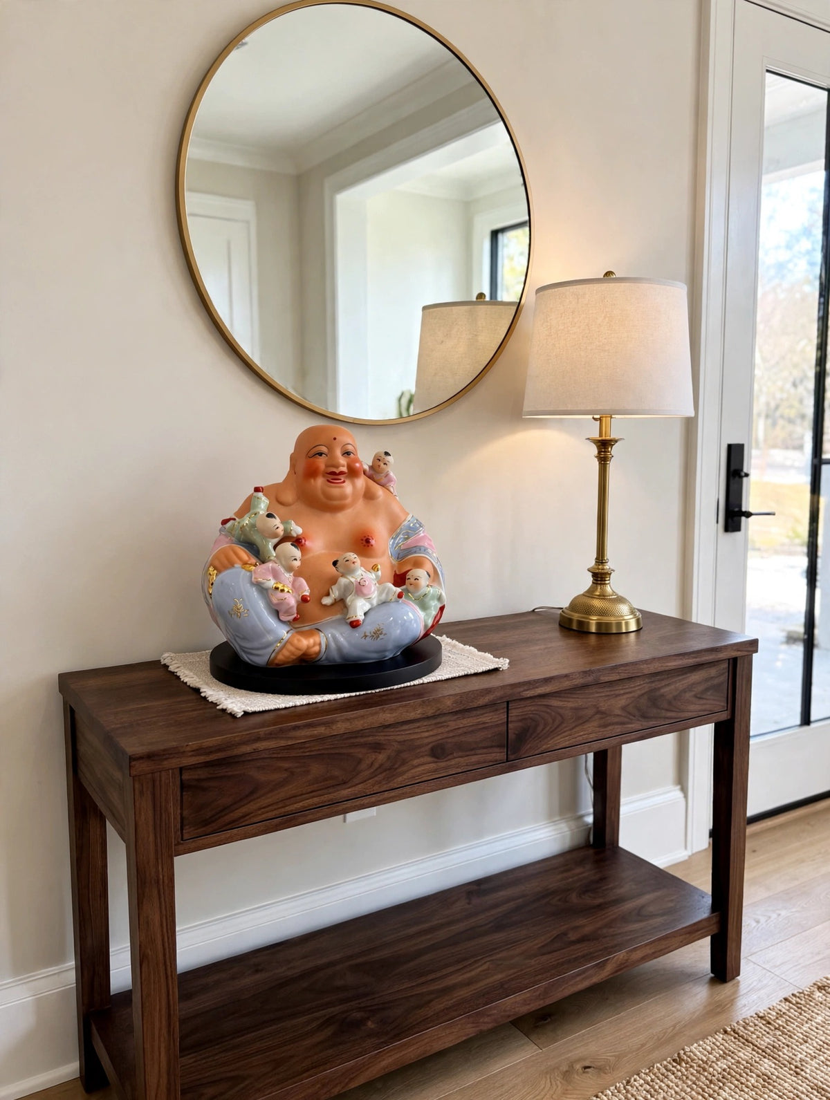 Styled lifestyle photo — the porcelain Buddha with five children on a dark wood console table in a bright entryway (display inspiration)