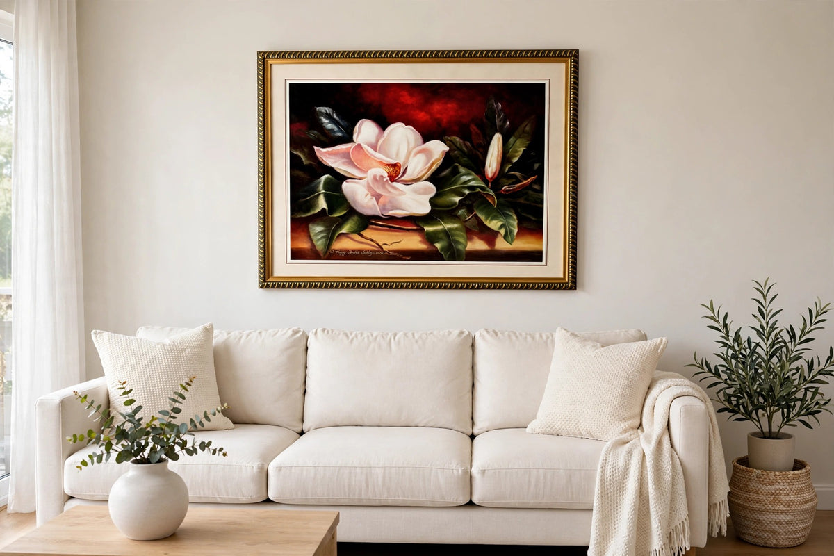 Styled lifestyle photo — the framed magnolia print above a cream sofa in a bright living room (display inspiration)