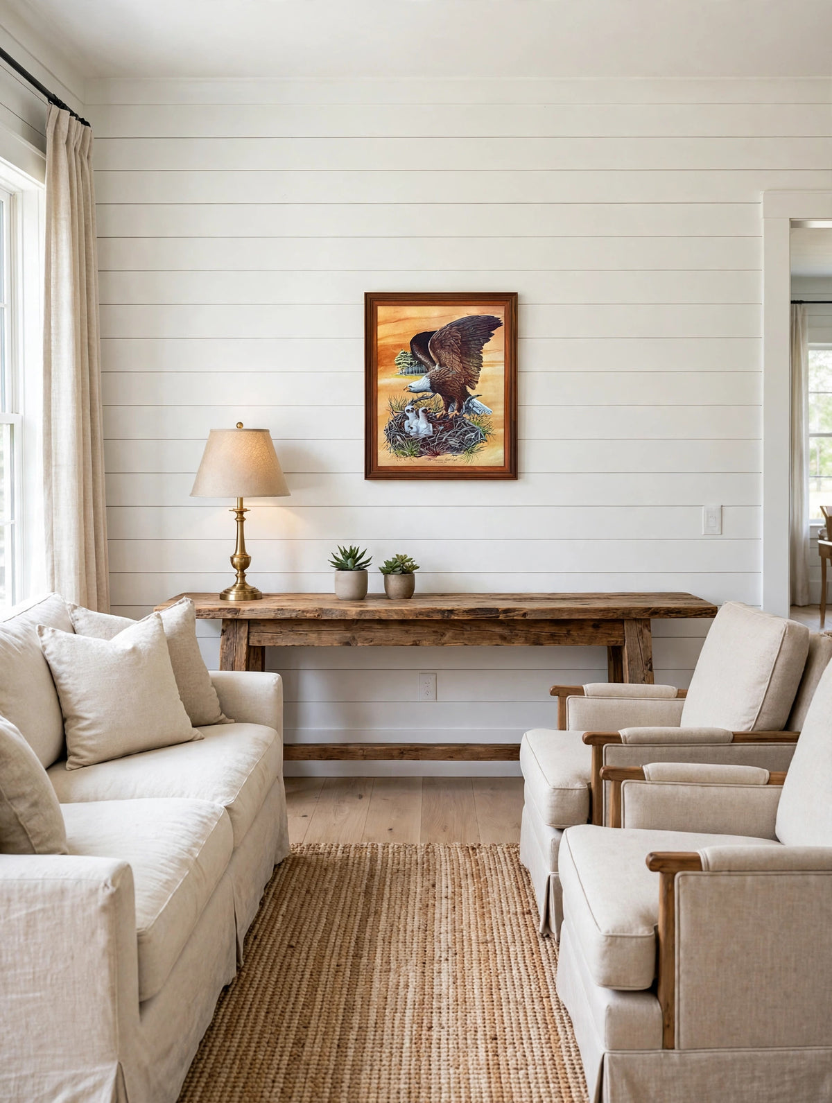 Styled lifestyle photo — the framed Robert Nipp bald eagle print above a rustic wooden console in a bright lodge-style living room (display inspiration)