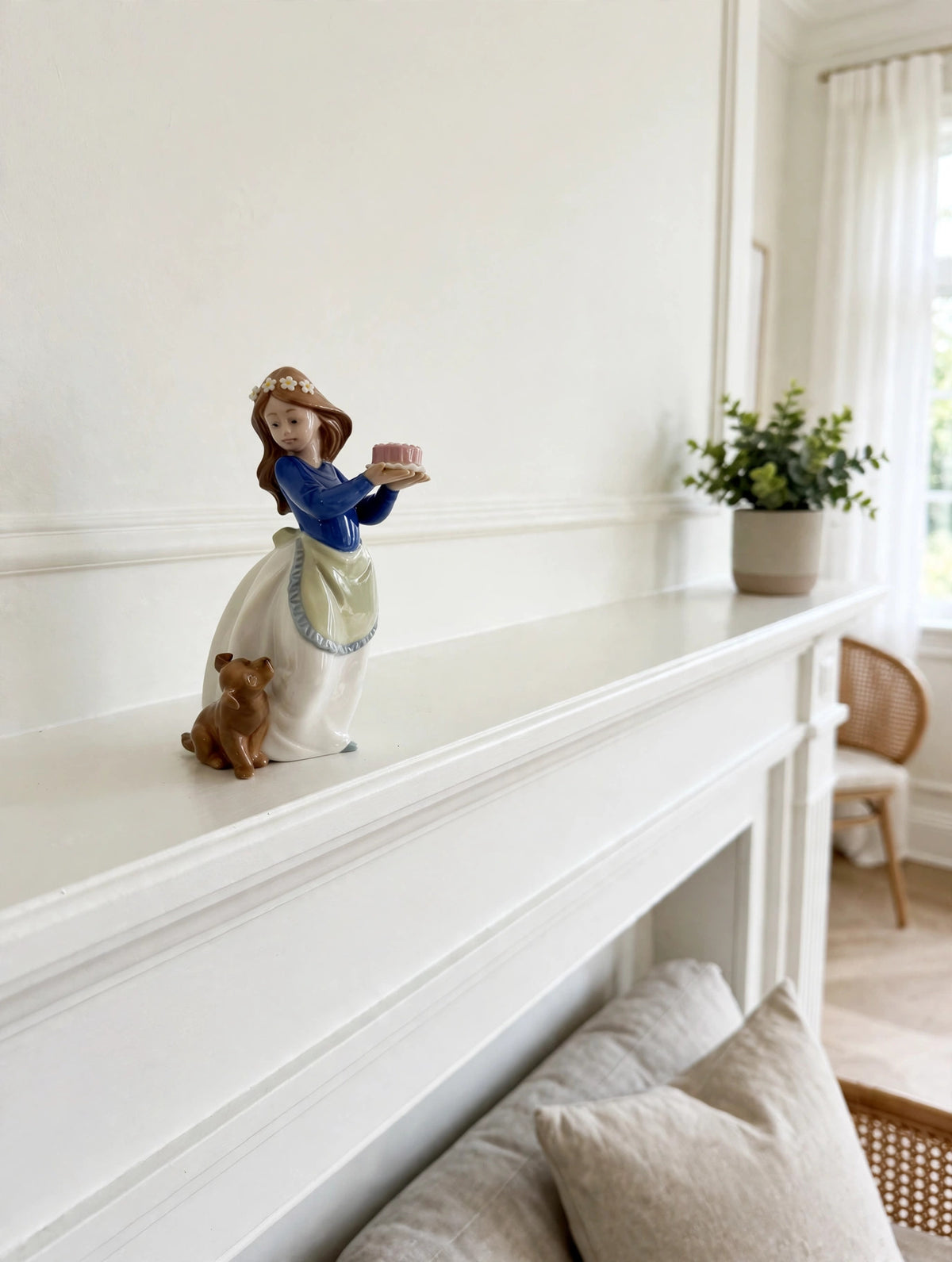 Styled lifestyle photo — the NAO "Puppy's Birthday" figurine on a white fireplace mantel in a bright living room (display inspiration)