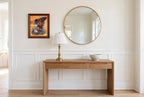 Styled lifestyle photo — the framed Robert Nipp bald eagle print above a wooden console table beside a round mirror in a bright entryway (display inspiration)