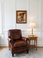 Styled lifestyle photo — the framed Robert Nipp bald eagle print above a leather club chair in a bright study (display inspiration)