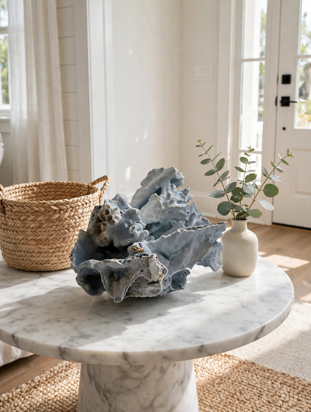 Large natural blue coral specimen on a marble entryway table with a woven basket and eucalyptus (styled display inspiration)