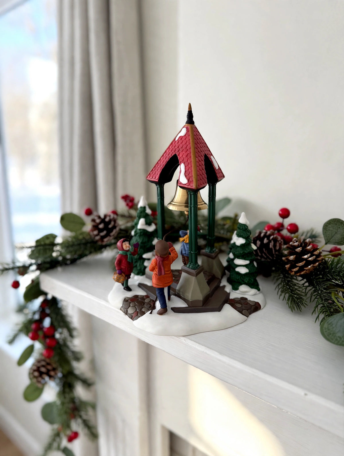 Department 56 Christmas Bells, 1996 Special Event Piece, Heritage Village Collection – shown on a bright Christmas mantel with garland and pine cones (styled display inspiration)