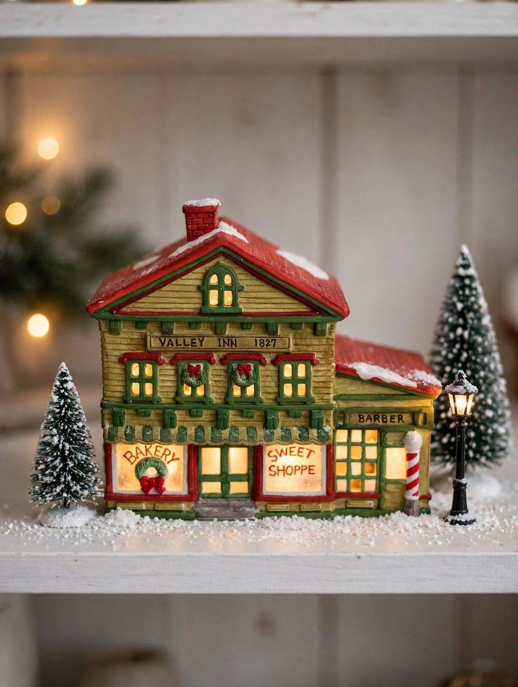 Sweet Shoppe and Bakery on a shelf with miniature pines and a lamppost, windows glowing - styled display inspiration