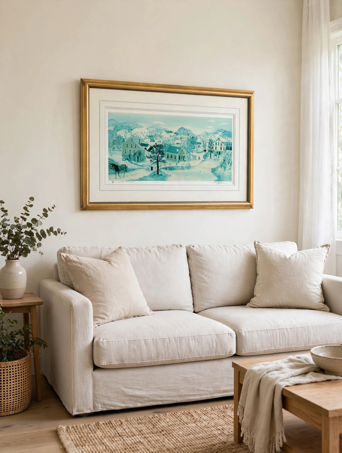Styled lifestyle photo — the framed School House Pond lithograph hanging above a linen sofa in a bright living room with cream walls (display inspiration)