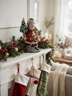 Styled lifestyle photo — display inspiration: Today's Nast Santa figurine on a fireplace mantel with garland, red berries and Christmas stockings