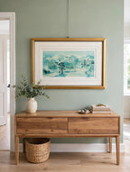 Styled lifestyle photo — the framed School House Pond lithograph hanging above a wooden console table in a bright entryway with sage green walls (display inspiration)