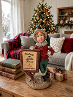 Styled lifestyle photo — the Signature Piece on a wooden coffee table with a stack of vintage books and a wrapped gift, a plaid-throw sofa and lit Christmas tree behind (display inspiration)