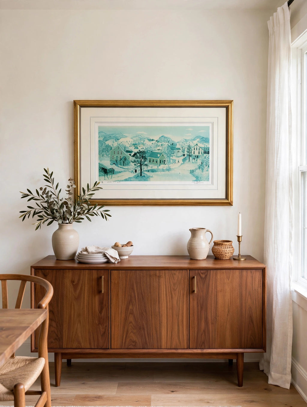 Styled lifestyle photo — the framed School House Pond lithograph hanging above a walnut sideboard in a bright dining room (display inspiration)