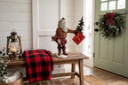 Styled lifestyle photo — display inspiration: Pioneer Santa figurine on an entry bench with a wreath and plaid throw