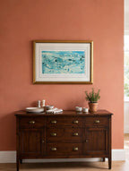 Styled lifestyle photo — the framed Shepherd's Nob lithograph hanging above a dark wood sideboard in a bright dining room with terracotta walls (display inspiration)