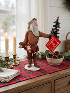 Styled lifestyle photo — display inspiration: Pioneer Santa figurine on a farmhouse sideboard with a plaid runner and candles