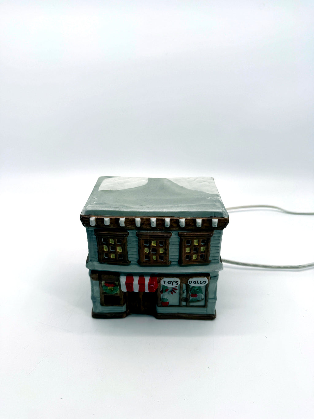 Ceramic Christmas village Toy and Doll shop, front view from above showing the snow-covered roof