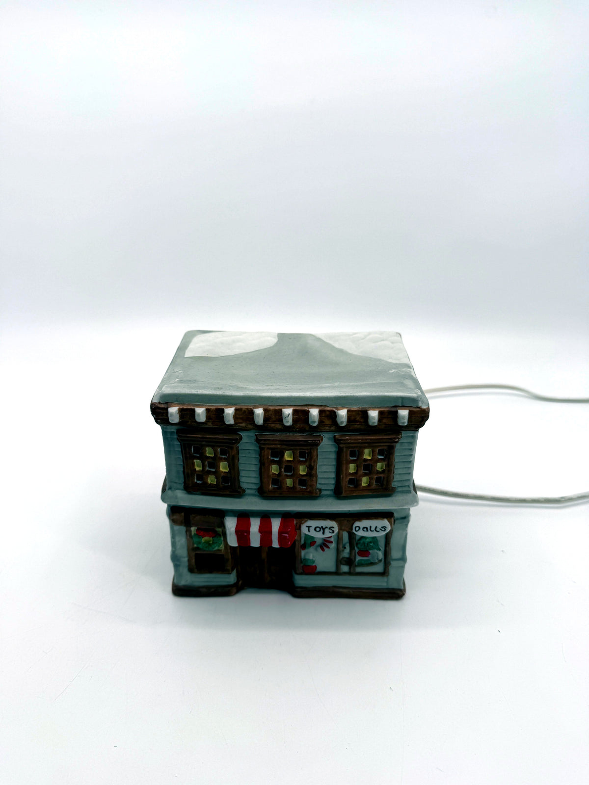 Ceramic Christmas village Toy and Doll shop, front view from above showing the snow-covered roof