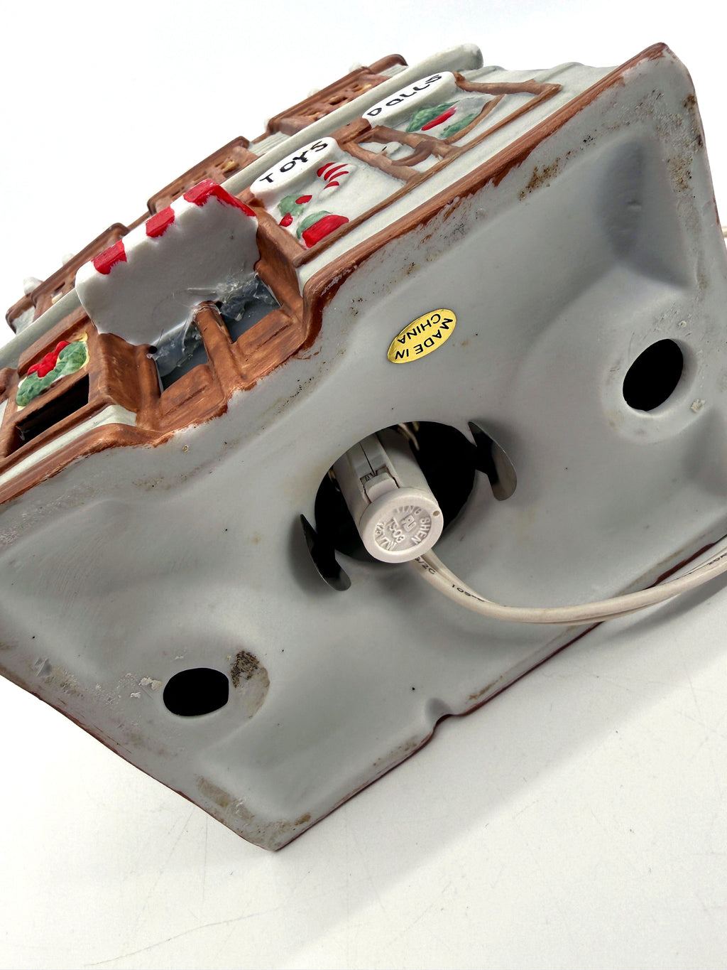Ceramic Christmas village Toy and Doll shop, underside showing the light socket, cord and Made in China sticker