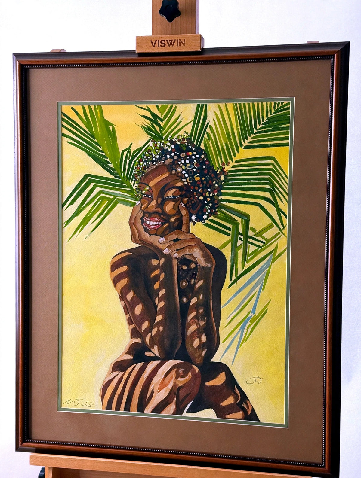 Signed tropical woman portrait in a dark wood frame with tan and green double matting — smiling woman with beaded hair among green palm fronds on a yellow ground, dappled light patterning across the figure; signature at lower left and monogram at lower right of the artwork