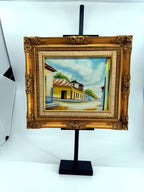 1984 signed oil on canvas Venezuelan street scene, framed — front view on the stand, wider shot
