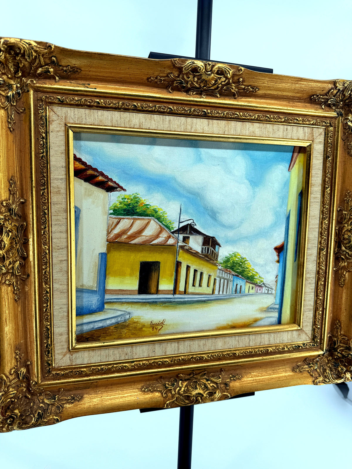 1984 signed oil on canvas Venezuelan street scene, framed — front view from a left angle