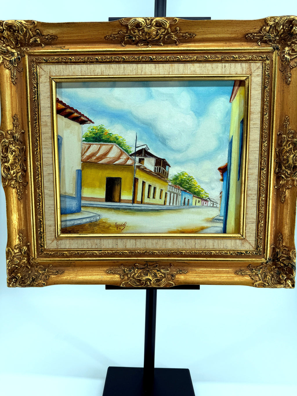 1984 signed oil on canvas Venezuelan street scene, framed — front view on the stand